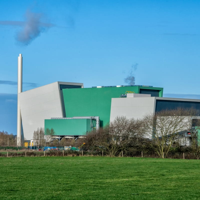 Javelin Park waste incinerator near Gloucester, England, with its industrial processing buildings and chimney, illustrating how carbon capture technologies can help waste-to-energy facilities reduce CO₂ emissions and support cleaner industrial operations.